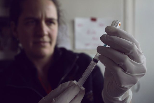 A medical volunteer prepares to administer a vaccine for tetanus